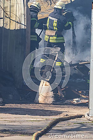 A strong and brave fireman rescues a burning building using water in a fire operation. Fireman in a fire protection suit. Stock Photo