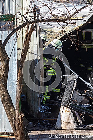 A strong and brave fireman rescues a burning building using water in a fire operation. Fireman in a fire protection suit. Editorial Stock Photo