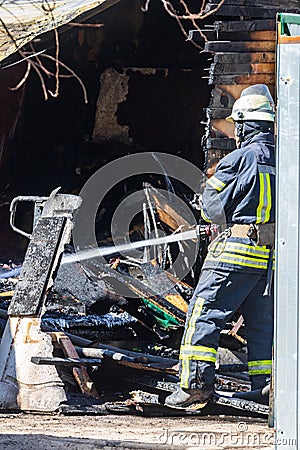 A strong and brave fireman rescues a burning building using water in a fire operation. Fireman in a fire protection suit. Editorial Stock Photo