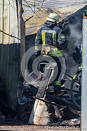 A strong and brave fireman rescues a burning building using water in a fire operation. Fireman in a fire protection suit. Stock Photo
