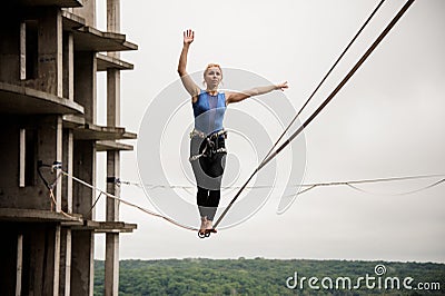 Strong and brave young woman balancing on a slackline Stock Photo