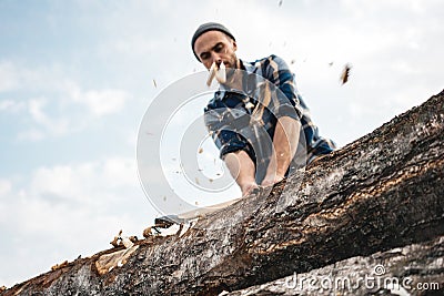 Strong and brutal lumberjack with ax in his hands chops tree in forest, wood chips fly apart Stock Photo