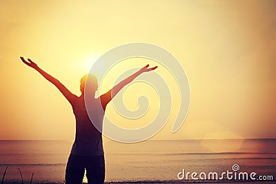 Strong confident woman open arms sunrise seaside Stock Photo