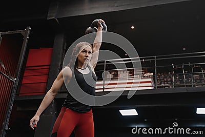 Strong crossfit woman exercising with a kettlebell at the gym. Female doing functional training Stock Photo