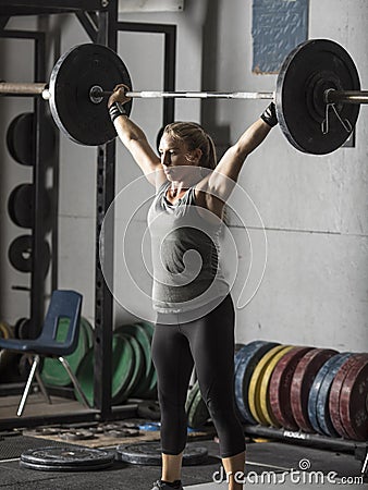 Strong female weight lifter with barbell over her head Stock Photo