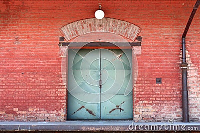 Strong rusted metal doors on red brick building connected to trucks unloading bay Stock Photo