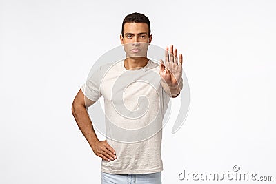 Strong handsome security guy pulling hand in stop motion, look assertive and serious, prohibit tresspassing, demand id Stock Photo