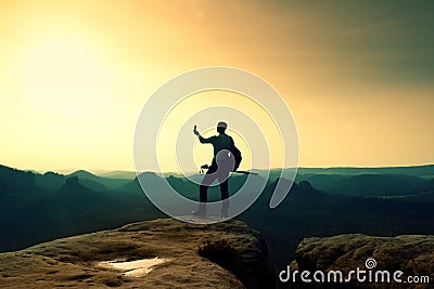 Strong hiker taking photo with smart phone at mountain peak. Marvelous daybreak. Stock Photo