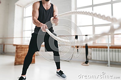 Strong male athlete doing exercises with rope at crossfit gym Stock Photo