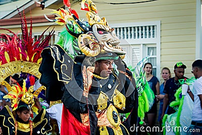 Strong man in bright costume carries scary mask by city street at dominican carnival Editorial Stock Photo
