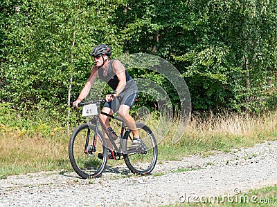 Strong man on light black trekking bike is riding on gravel road Editorial Stock Photo