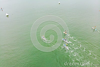 Strong men floating on a SUP boards in a beautiful bay on a sunny day. Aerial view of the men crosses the bay using the Stock Photo
