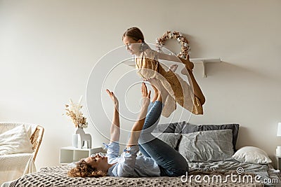 Strong mother lifting adorable little daughter on legs, having fun Stock Photo