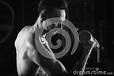 Strong Muscular man with naked torso abs working out in gym doing exercises with dumbell at biceps Stock Photo