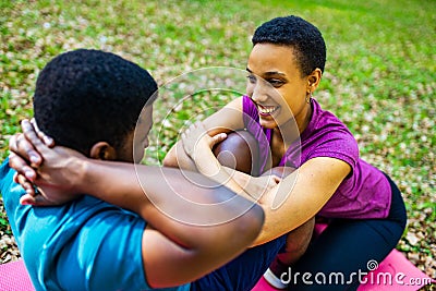 Strong and powerful afro american couple in love are working out abs exercises outside in park or forest Stock Photo