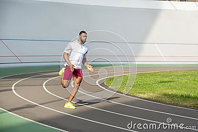 Strong purposeful sportive man on the running track Stock Photo