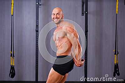 Strong ripped bold man demonstrating big muscles in gym. Sport, Stock Photo