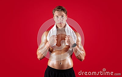 Strong shirtless sportsman with towel after shower, bath or sauna posing on red studio background Stock Photo