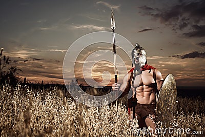 Strong Spartan warrior in battle dress with a shield and a spear Stock Photo