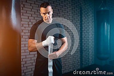 Athletic boxer man bandage hand and preparing for training or fighting in gym Stock Photo