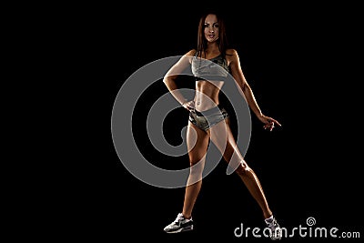 Strong tanned beautiful sports girl on a black background. Stock Photo