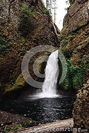 Strong waterfall falling from the middle of enormous rocks and flowing in the river Stock Photo