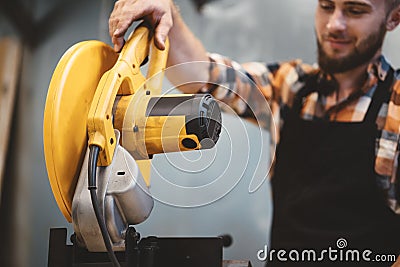 Strong worker using angular grinding machine in workshop. Servicing of machines Stock Photo