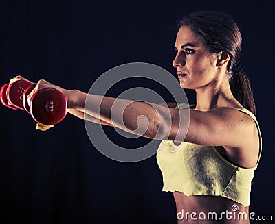 Strong young woman doing dumbbell front raises Stock Photo