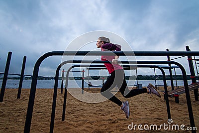 Strong Young woman goes sports outside. Lady pulling up in workout area. Stock Photo