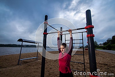 Strong Young woman goes sports outside. Lady pulling up in workout area. Stock Photo