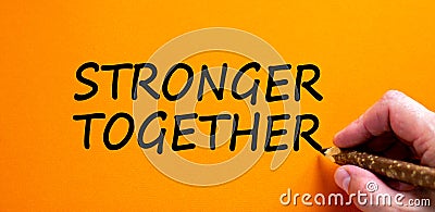 Stronger together symbol. Businessman writing `stronger together`, isolated on orange background. Business, motivational and Stock Photo