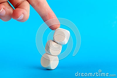 Structure collapsing, knocked over. Wooden cube tower pushed by human finger coming from above. Market collapse, crisis Stock Photo