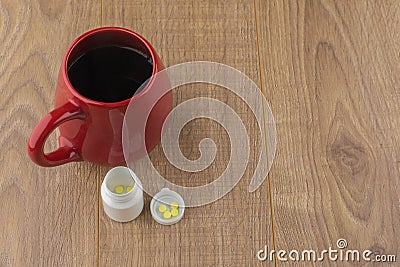 The struggle against Drowsiness : caffeine pills near the pill boxes and red Cup of strong coffee on wooden table Stock Photo