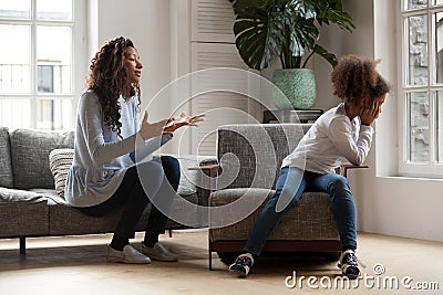 Stubborn african kid ignoring mom scolding, parent and child con Stock Photo