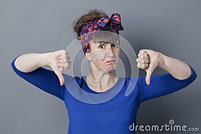 Stubborn young woman with thumbs down sulking for childish disappointment Stock Photo