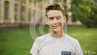 Student against university smiling at camera, foreign exchange program for teens Stock Photo