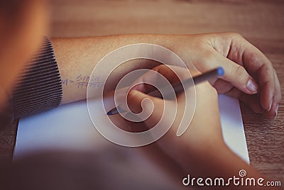 Student cheating during exam in university, reading cheat sheet with formula written on hand Stock Photo