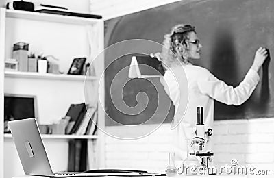 Student girl writing answer at blackboard. beaker and microscope. student doesnt use laptop. biology lesson. Science and Stock Photo