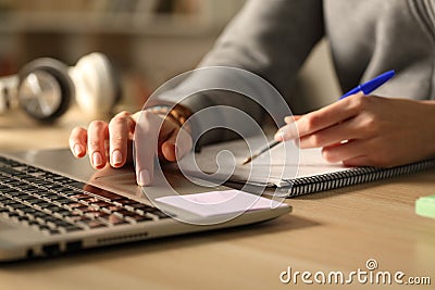 Student hands comparing laptop content and notes at night Stock Photo