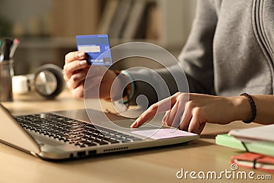 Student hands paying with credit card on laptop at night Stock Photo