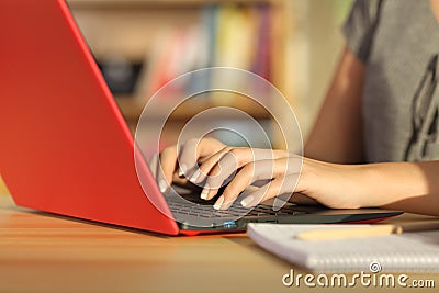 Student hands writing in a red laptop at home Stock Photo