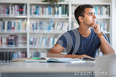 Handsome student reading a book for his class in a bright modern library Stock Photo