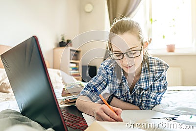 Student is passing online lesson on the Internet at home lying on a bed. Remote learning in schools and universities Stock Photo