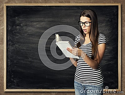 Student Reading Book over Blackboard Background, Amazed Woman Stock Photo