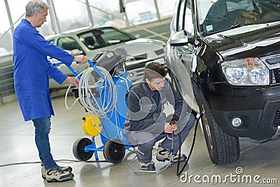 Student and senior mechanic checking tyre pressure at automotive shcool Stock Photo