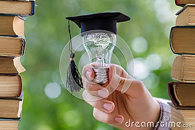 Student shows light bulb in the cap academic . Stock Photo