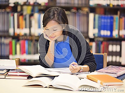 Student sitting and reading book in library Stock Photo