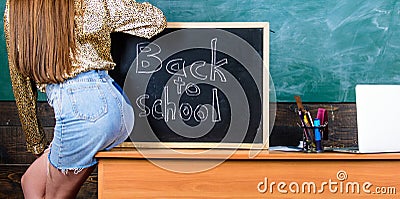 Student teacher mini skirt buttocks sit table blackboard inscription back to school. Girl denim skirt breaking Stock Photo