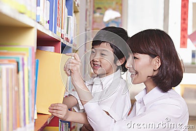 Student and Teacher Taking Book from a Bookshelf Stock Photo