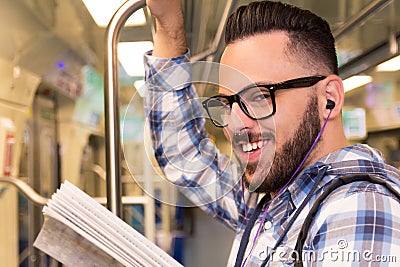 Student traveler with glasses reading book while riding to school by subway train. Concept of commute, effort, aspirations. Stock Photo